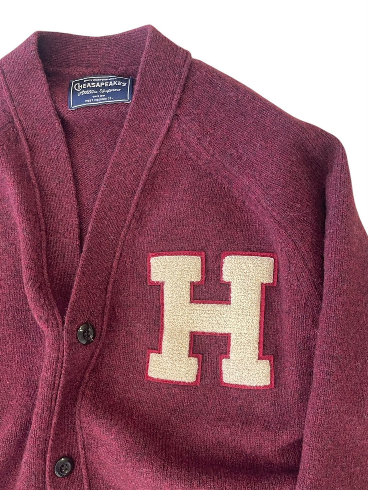 Dettaglio della maglia Burgundy e della patch H écru sul cardigan Chesapeake’s